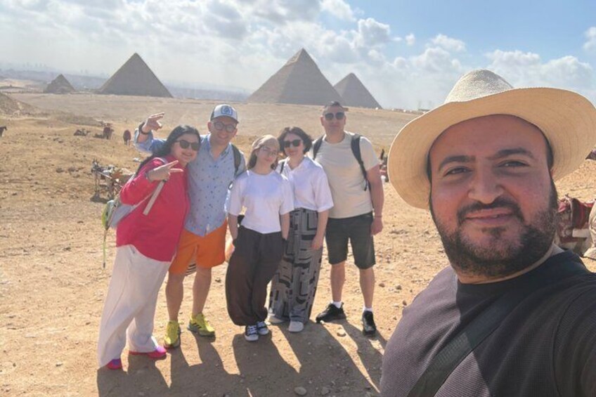 A group of people standing in a desert with pyramids in the background. 3