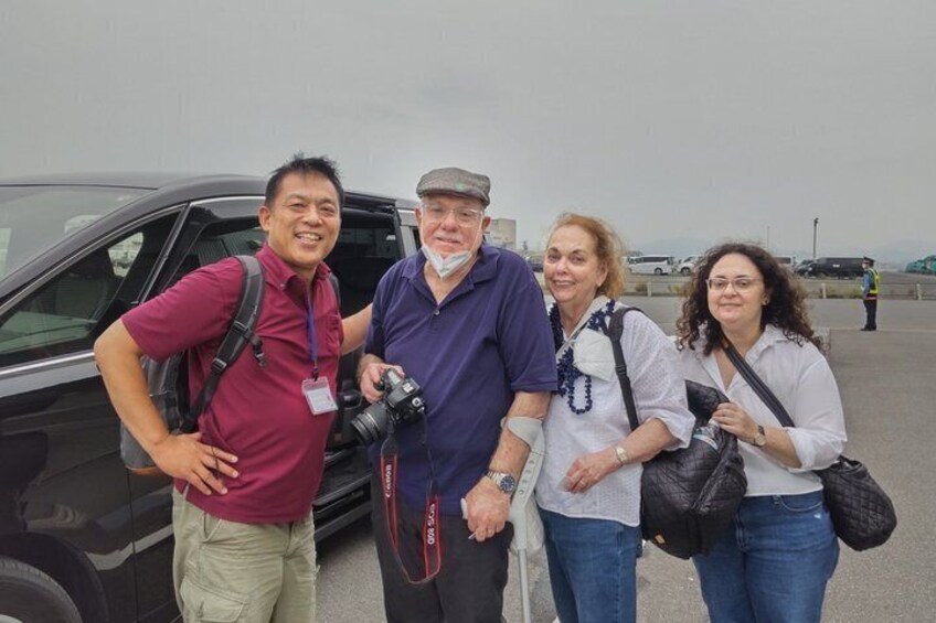 Four people standing in front of a black car with a camera. 4