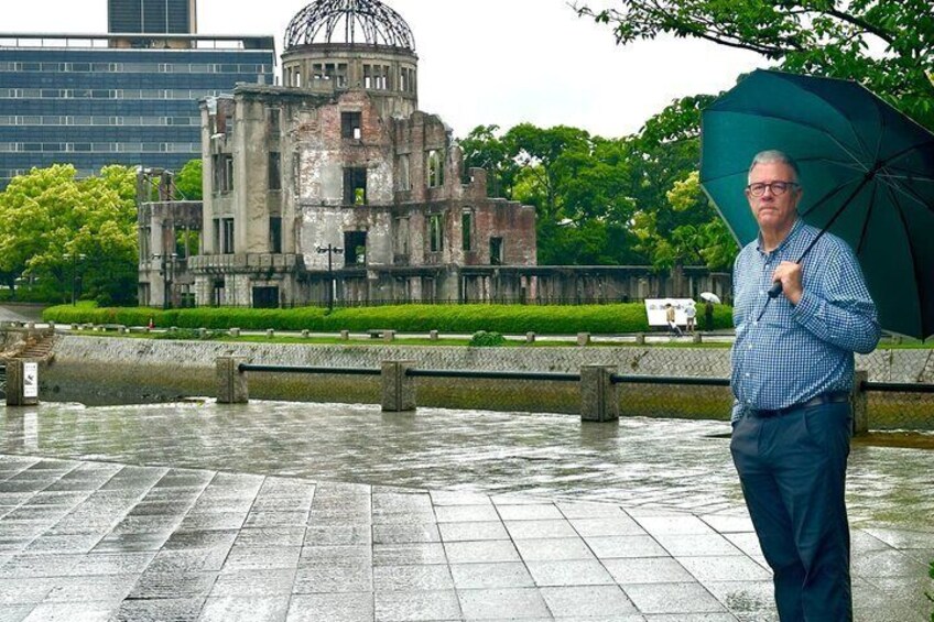 A man holding an umbrella, standing in front of a historic building with a dome, near a body of water. 5