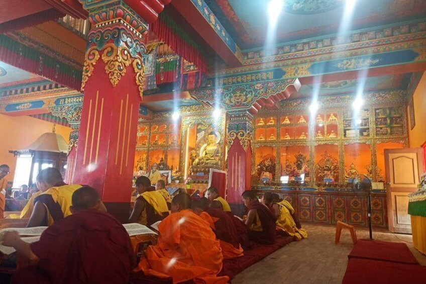 A group of monks in a brightly decorated temple with intricate designs and a central altar. 2