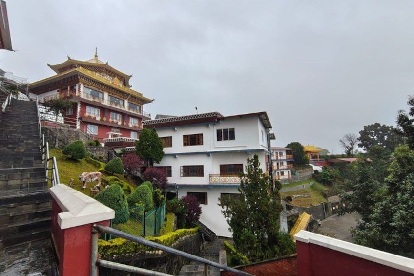 A traditional building with a red and white facade, a multi-story structure with balconies, and a staircase leading up to it. 2