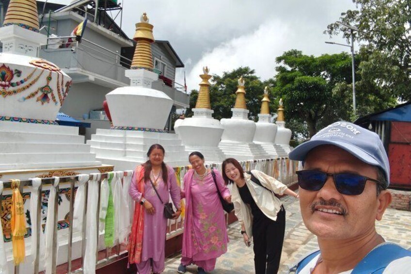 A group of people near a row of white stupas with golden tops, some with colorful decorations. 5