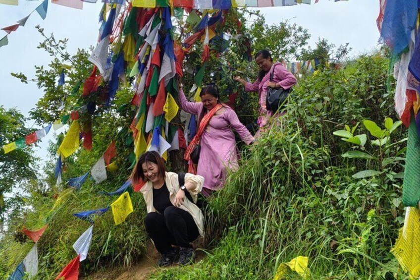 People climbing a grassy hill with colorful prayer flags. 3