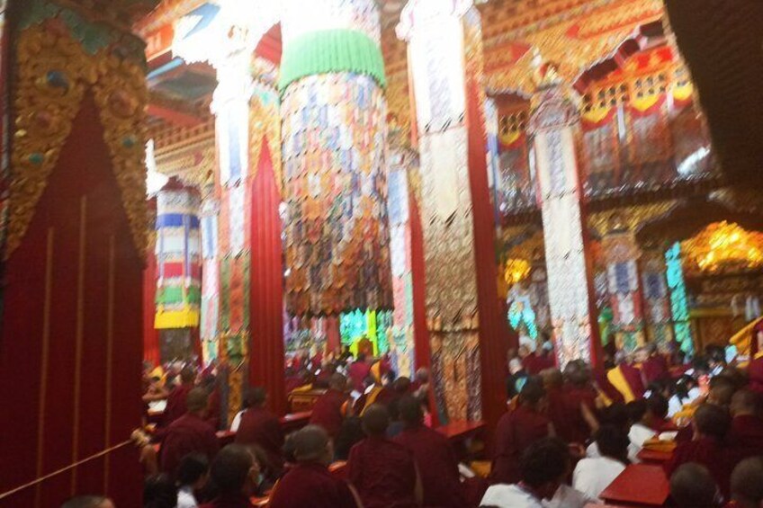 A crowded indoor space with ornate columns and a group of people seated. 3