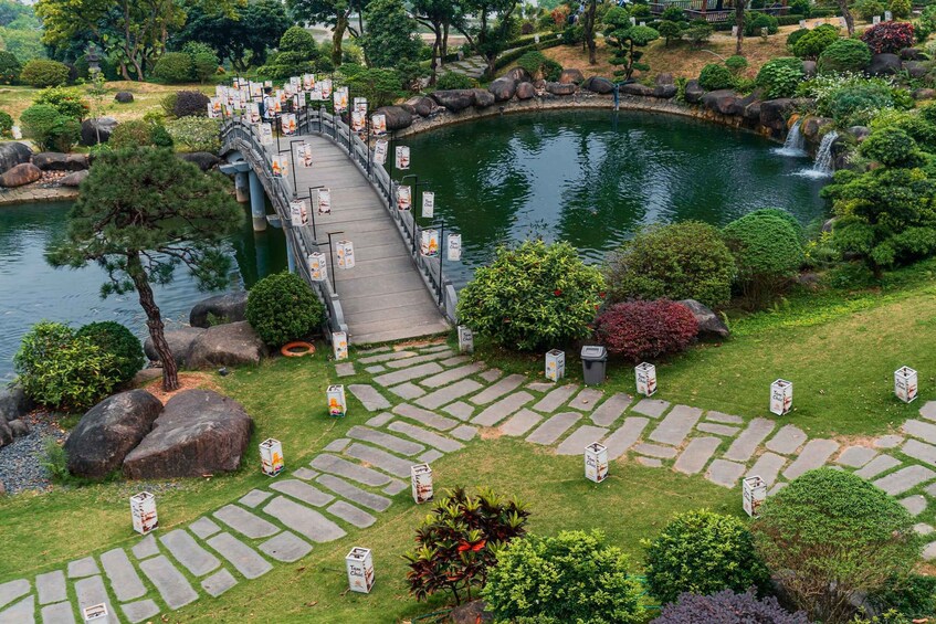A bridge over a pond with stone paths and greenery. 2