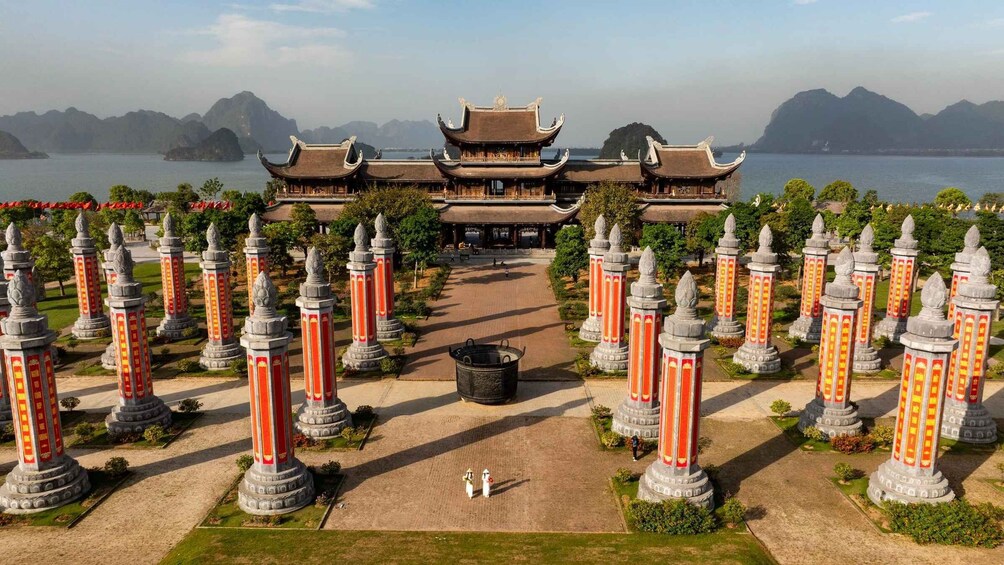 A traditional Chinese building with a symmetrical facade, surrounded by a garden with stone pillars and a clear view of the water and mountains in the background. 4