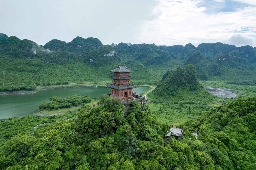 A pagoda on a mountain peak surrounded by lush greenery and a river. 1