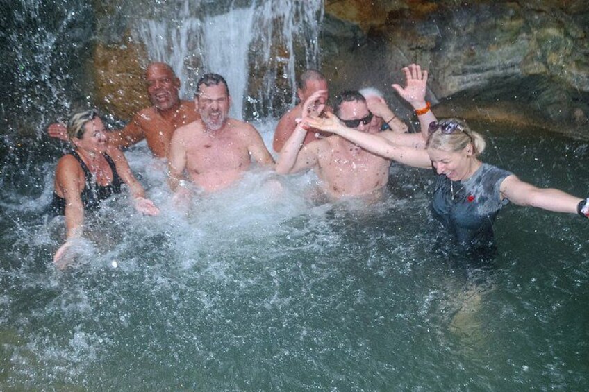 A group of people in a water body with a waterfall in the background. 4