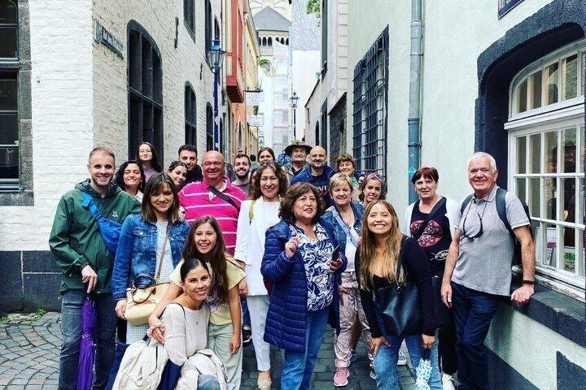 A group of people standing on a cobblestone street in a narrow alleyway with buildings on either side. 5