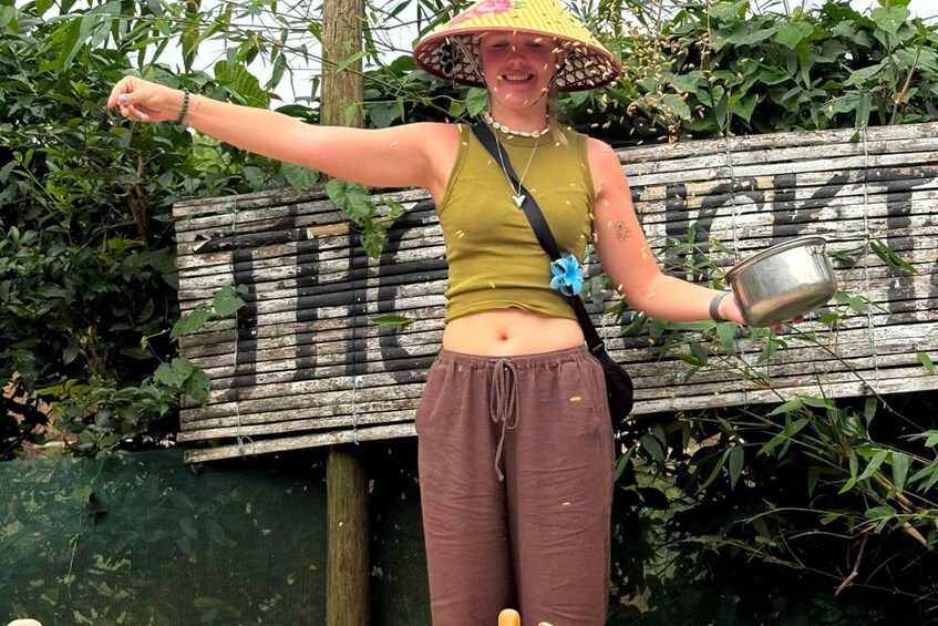 A person standing outdoors, wearing a hat and holding a metal container. 2