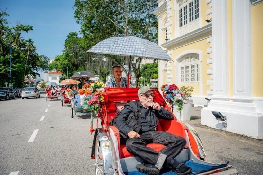 A person in a wheelchair with a red umbrella, another person in a black jacket, and a building with white columns. 2