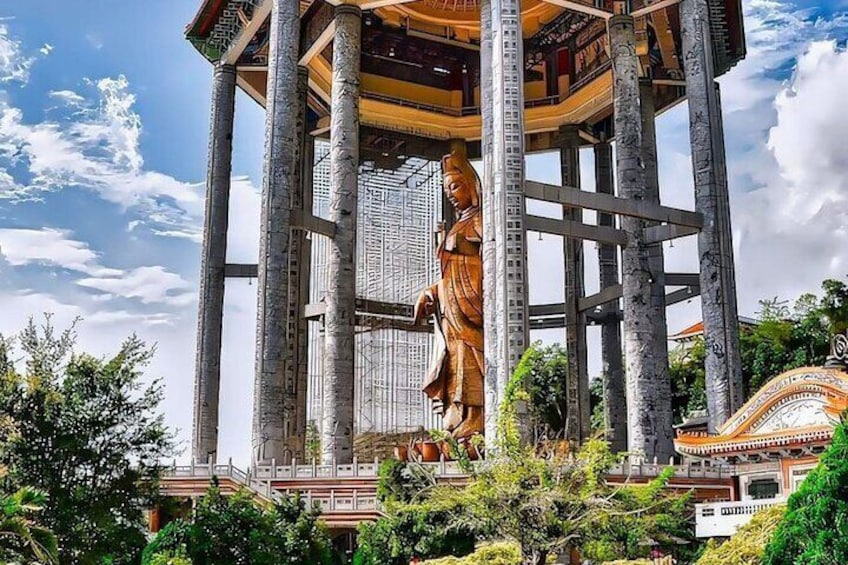 A large golden statue on a multi-tiered structure with a temple in the background. 1