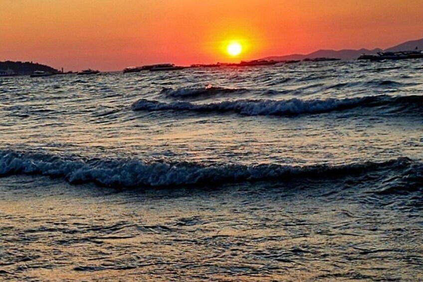 A sunset over the ocean with waves and distant land. 2