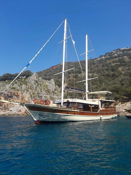 A sailing boat named 'Karagol' docked near rocky terrain with a clear sky. 1