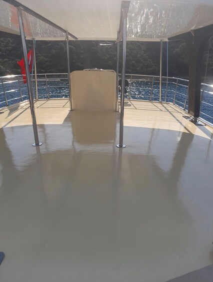 A covered outdoor area with metal railings and a beige floor, overlooking a body of water. 2