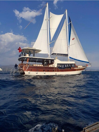 A sailing yacht with white sails and a wooden deck, sailing on the ocean. 5