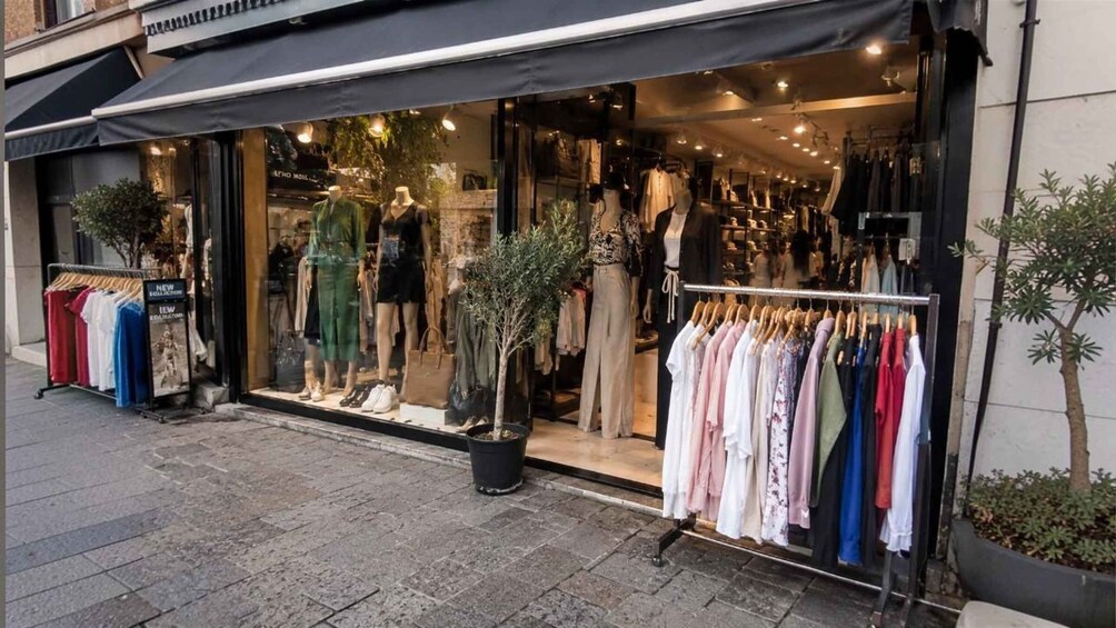 A clothing store with mannequins and racks of clothes outside. 5