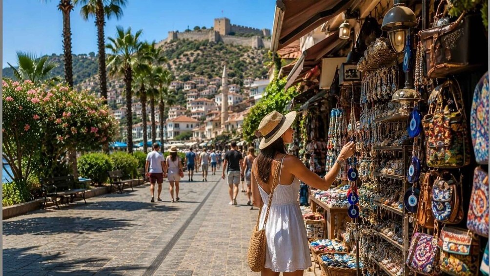 A bustling street market with people browsing stalls, palm trees, and a historic hilltop castle in the background. 3