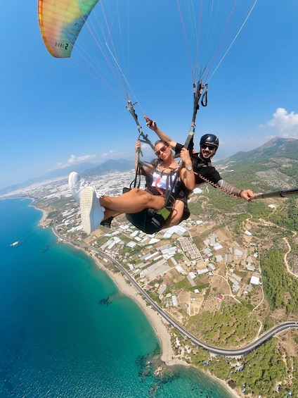 A person paragliding over a coastal area with a clear view of the coastline, buildings, and roads below. 1