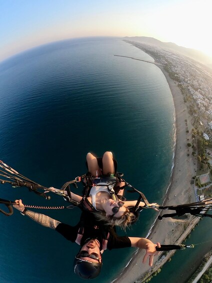 A person bungee jumping with a parachute, overlooking a coastal city and ocean. 3
