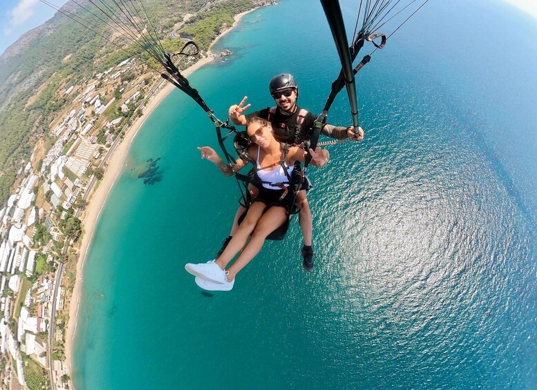 A person paragliding over a coastal area with a clear view of the beach and buildings below. 4
