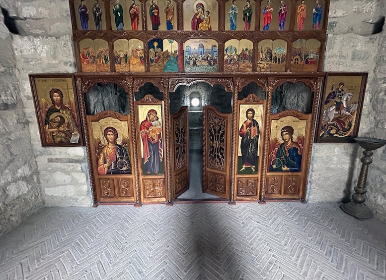 A religious iconostasis with multiple icons, a stone wall, and a patterned floor. 3