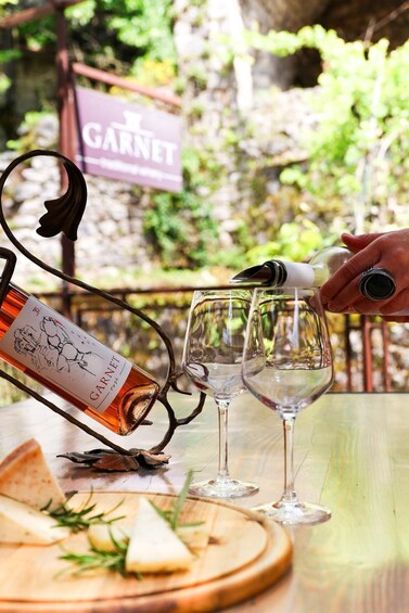 A wine bottle being poured into two wine glasses on a table with a sign reading 'Garnet' in the background. 3