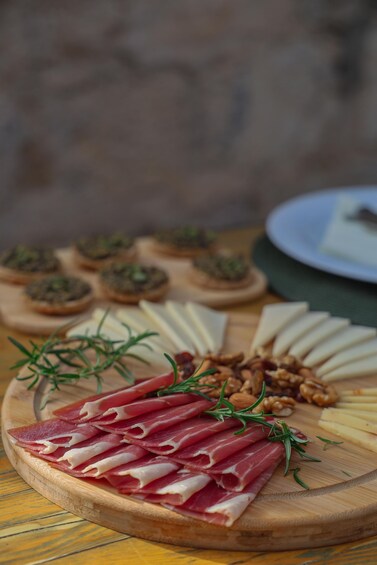 A charcuterie board with prosciutto, cheese, nuts, and small appetizers on a wooden board. 2