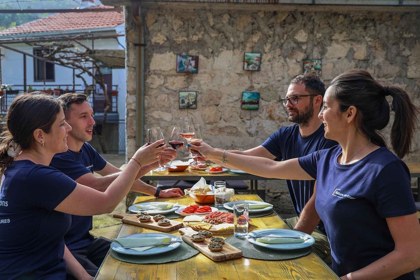 A group of people toasting with wine glasses at a wooden table with a stone wall background. 1