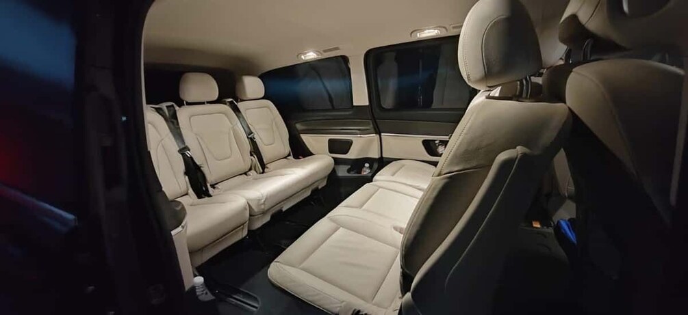 A vehicle interior with beige leather seats, a center console, and a rearview mirror. 3