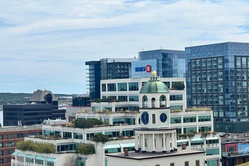 A cityscape with modern buildings, a prominent clock tower, and a clear sky. 1