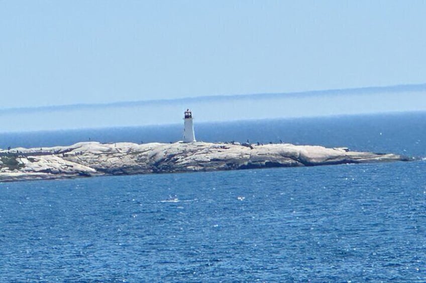 A lighthouse on a rocky outcrop with the ocean in the foreground. 4