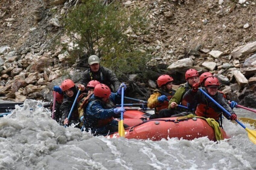 A group of people in a red inflatable raft navigating through a turbulent river. 2
