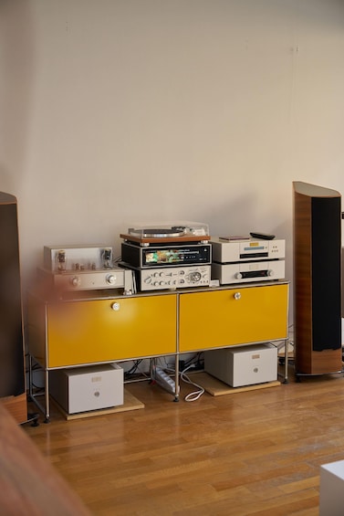 A vintage audio equipment setup on a yellow cabinet with a wooden floor. 2