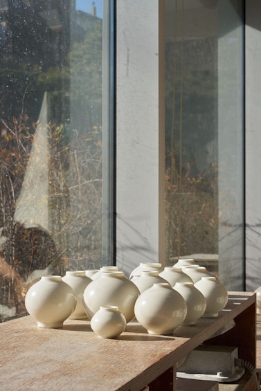 Ceramic vases on a wooden shelf by a window. 3