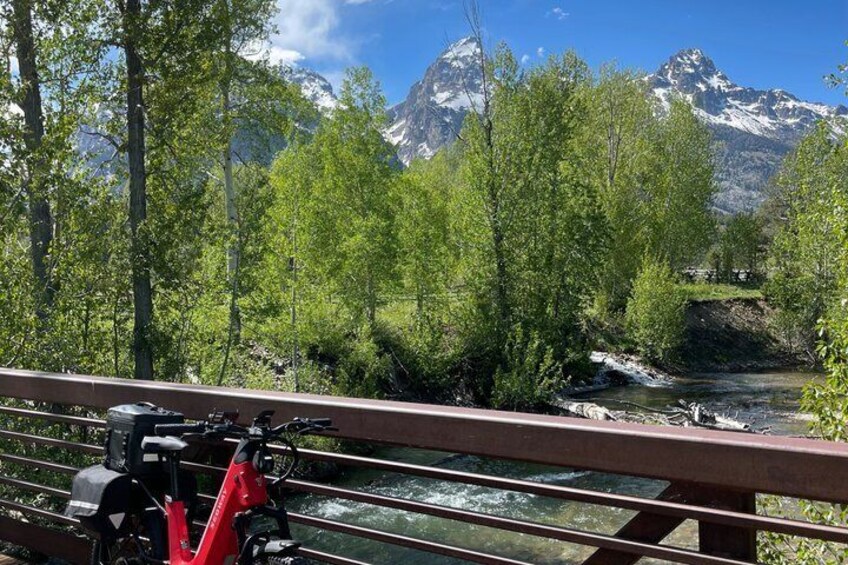 A red bicycle on a bridge with a river and mountains in the background. 2