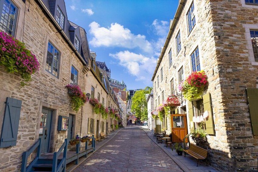 A cobblestone street lined with stone buildings, some with flower boxes. 2