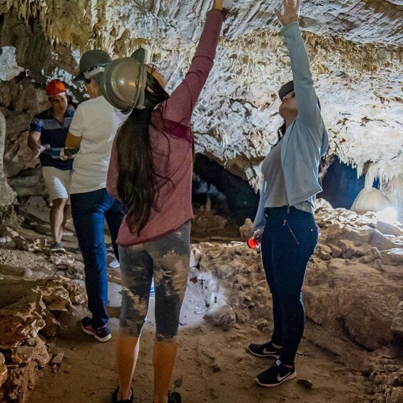 People exploring a cave with stalactites. 2