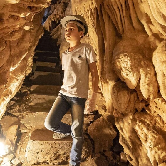 A person standing on a stone staircase inside a cave with stalactites. 5