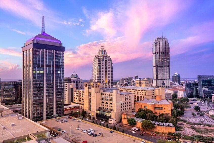 A cityscape with modern skyscrapers, a large building with a dome, and a parking lot. 1