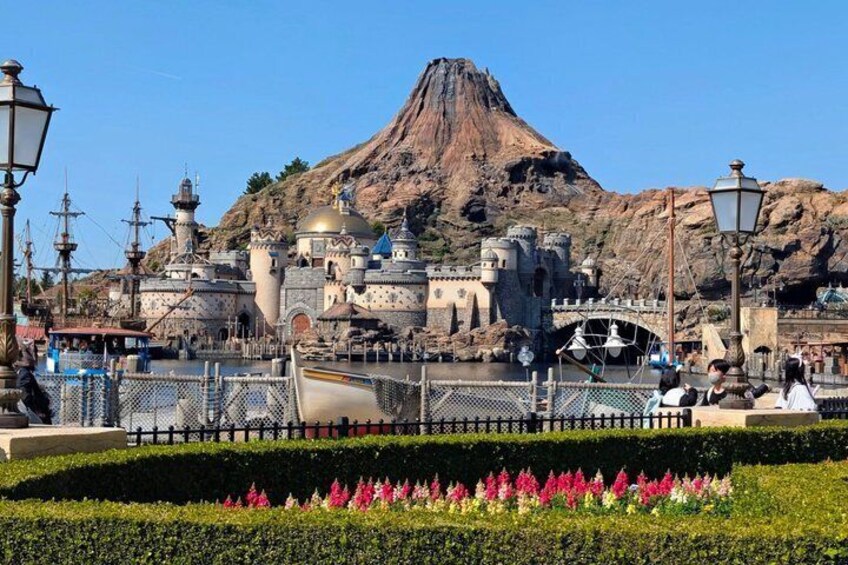 A theme park with a castle, a volcano, and a bridge. 1