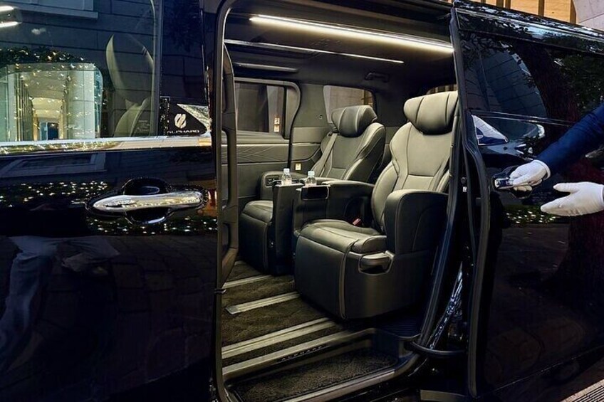 A luxury vehicle interior with a dark color scheme, leather seats, and a visible door handle. 3