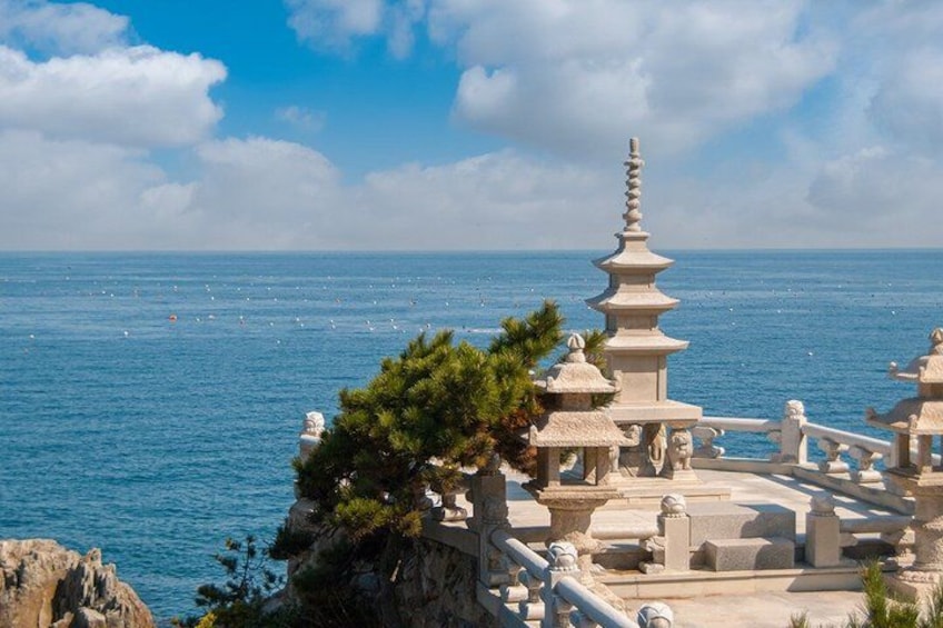 A coastal temple complex with a large pagoda, ocean view, and rocky terrain. 3