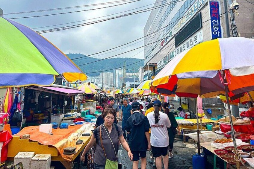A bustling outdoor market with colorful umbrellas and various stalls. 3