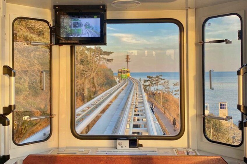 A train window with a view of a railway track, a bridge, and a coastal landscape. 5