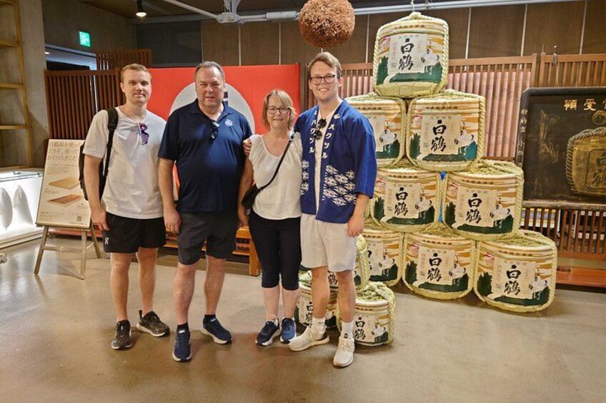 Four people standing in front of a display of stacked barrels. 4