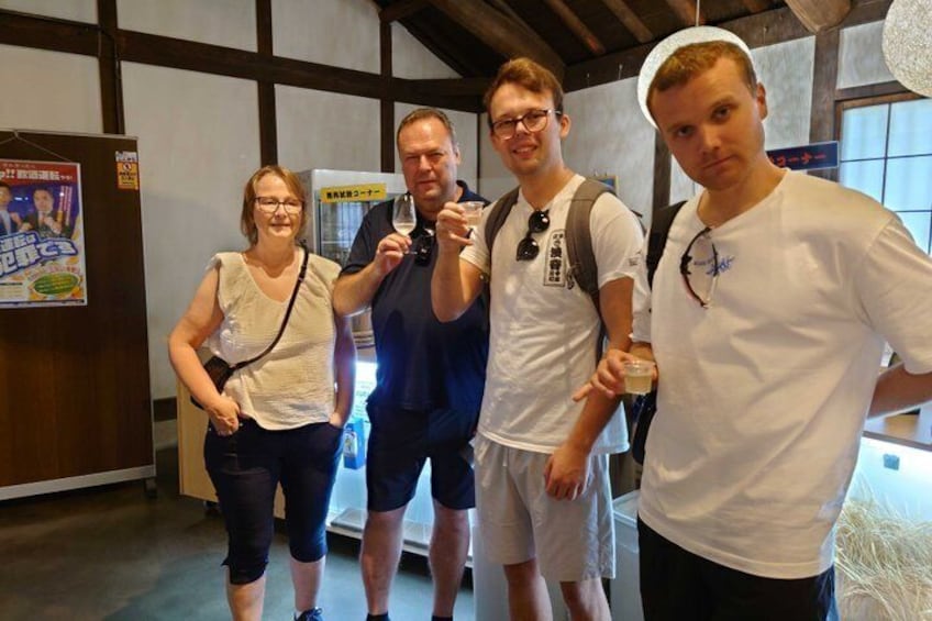 Four people in a room with wooden beams, a poster on the wall, and a vending machine. 3