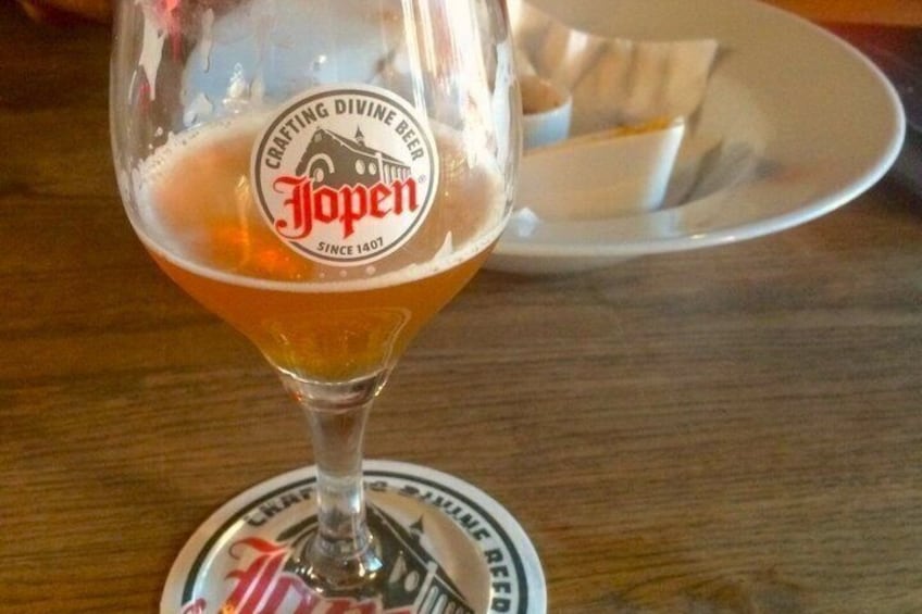 A glass of beer with a coaster featuring the Jopen logo. 4