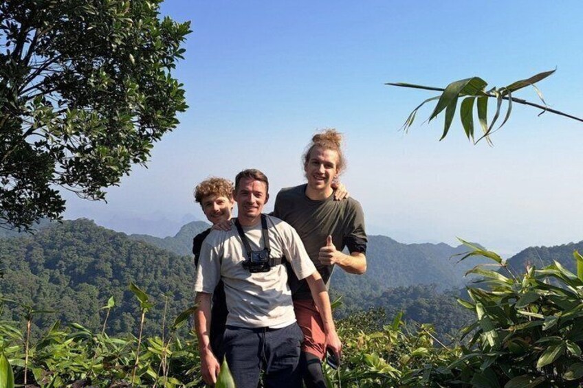 Three people standing on a hill with a mountainous landscape in the background. 5