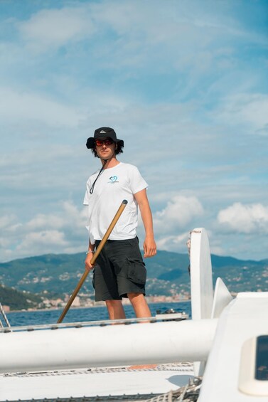 A person standing on a boat holding a paddle, with a clear sky and distant mountains in the background. 3